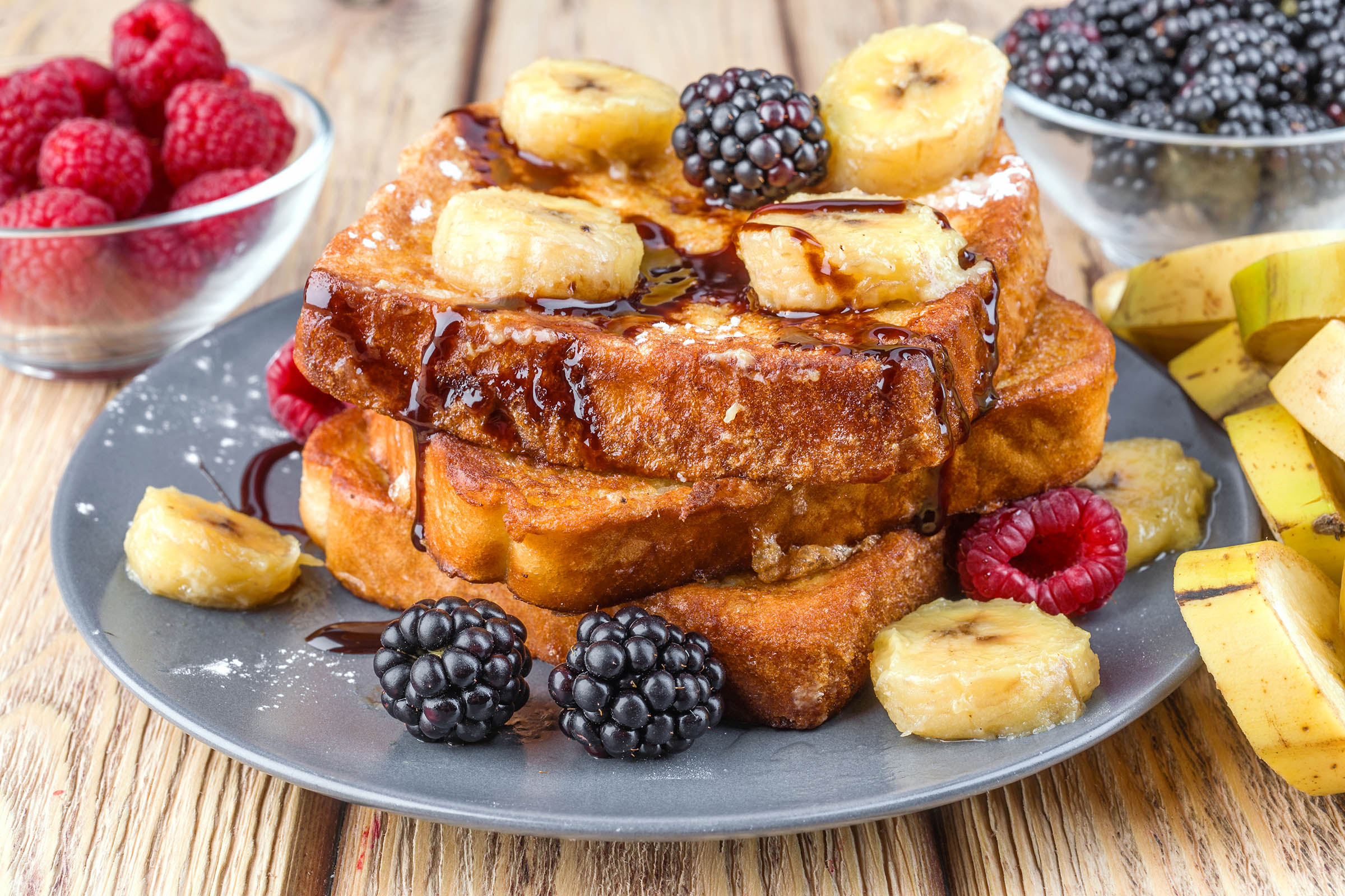 Stack of French toast with banana, blackberries and chocolate drizzle