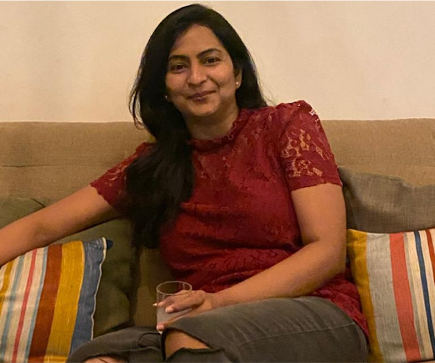 Client testimonial — woman in red top on a sofa