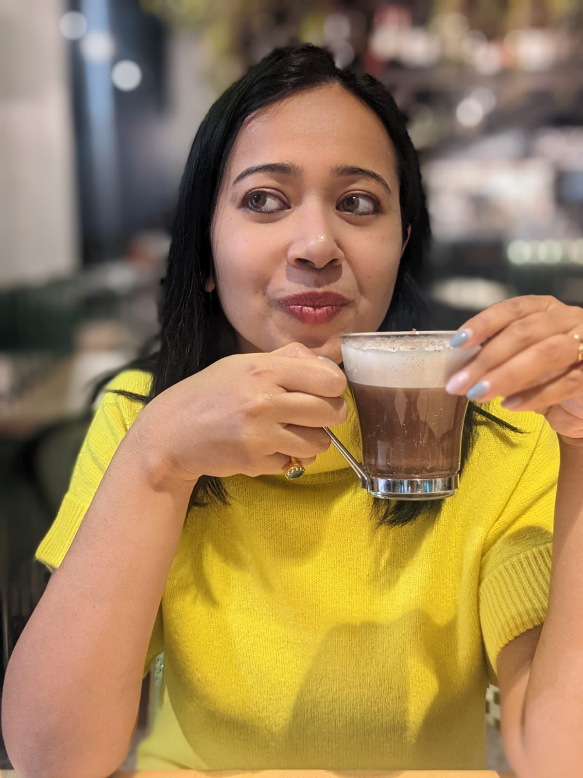 Aditi Guha in a yellow top holding a coffee