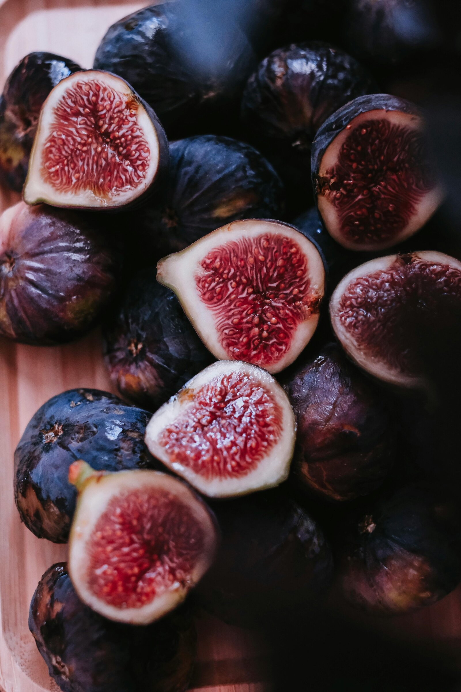 Fresh figs, some sliced open to reveal their rich red interior, on a wooden board — the signature à la Modon motif