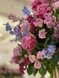 A lush arrangement of pink and purple roses, lilacs and delphinium
