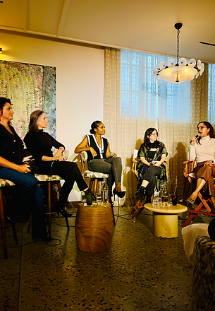 Five women seated in a panel discussion in a modern interior with art on the wall
