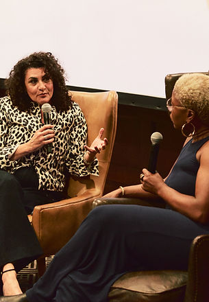Two women in conversation on stage, one holding a microphone