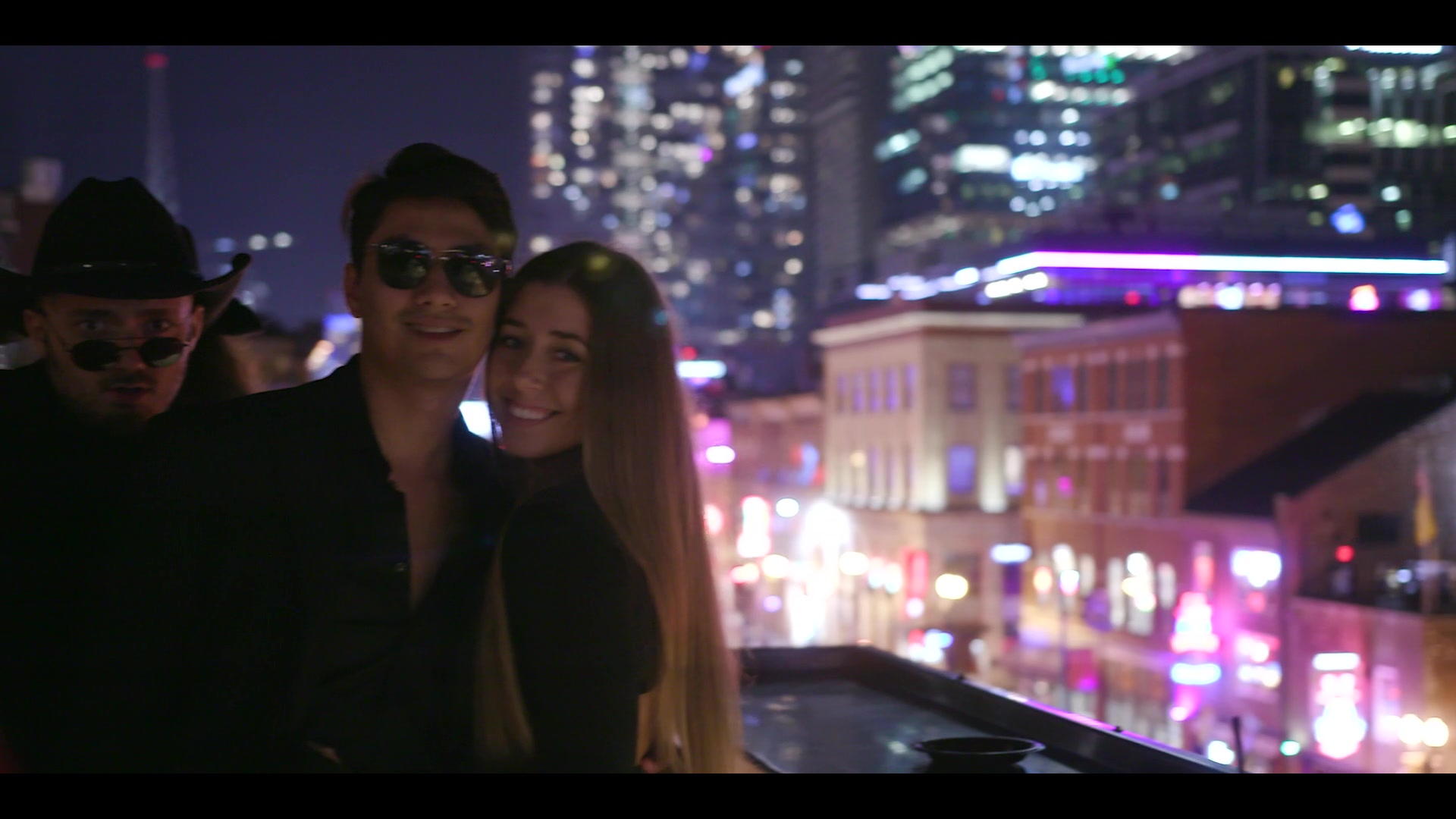 Group of students on a rooftop bar over a lit nightlife strip in Nashville