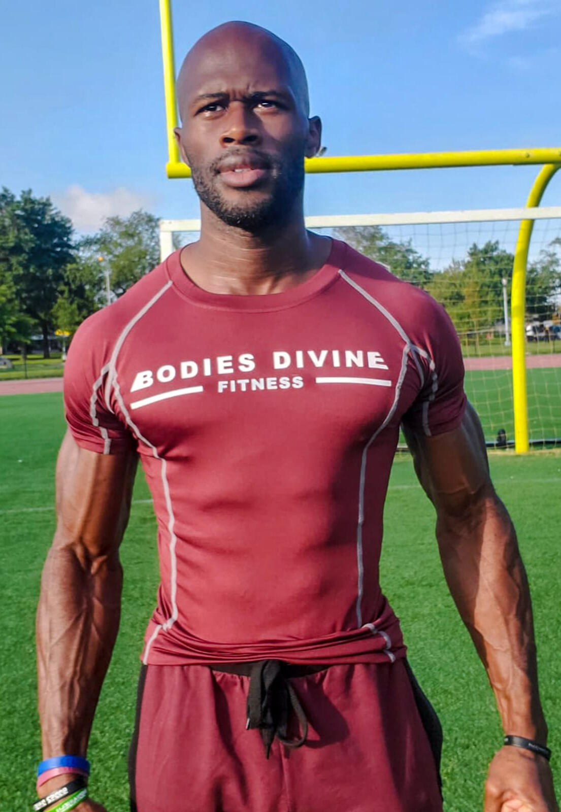 Coach Lord in a Bodies Divine Fitness shirt on a field