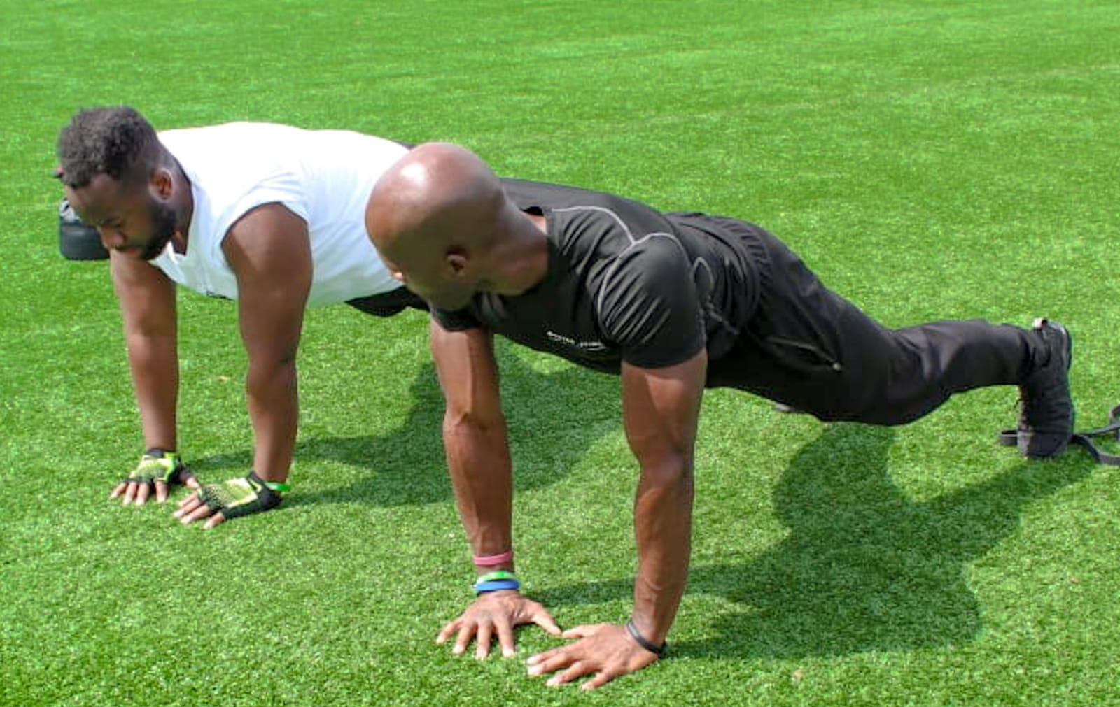 Two men doing push-ups on turf, one in a BDF shirt