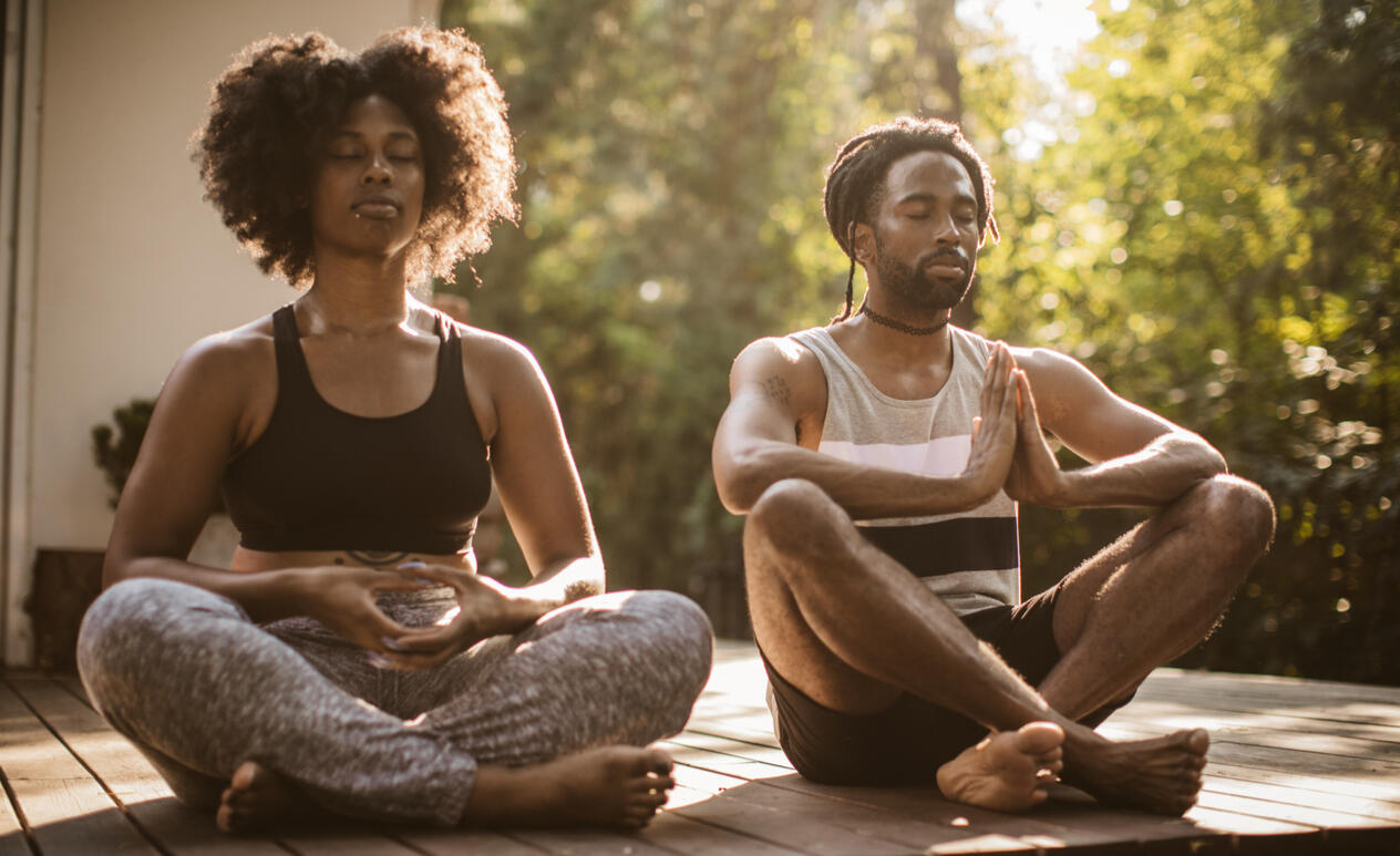 Couple meditating outdoors on a deck