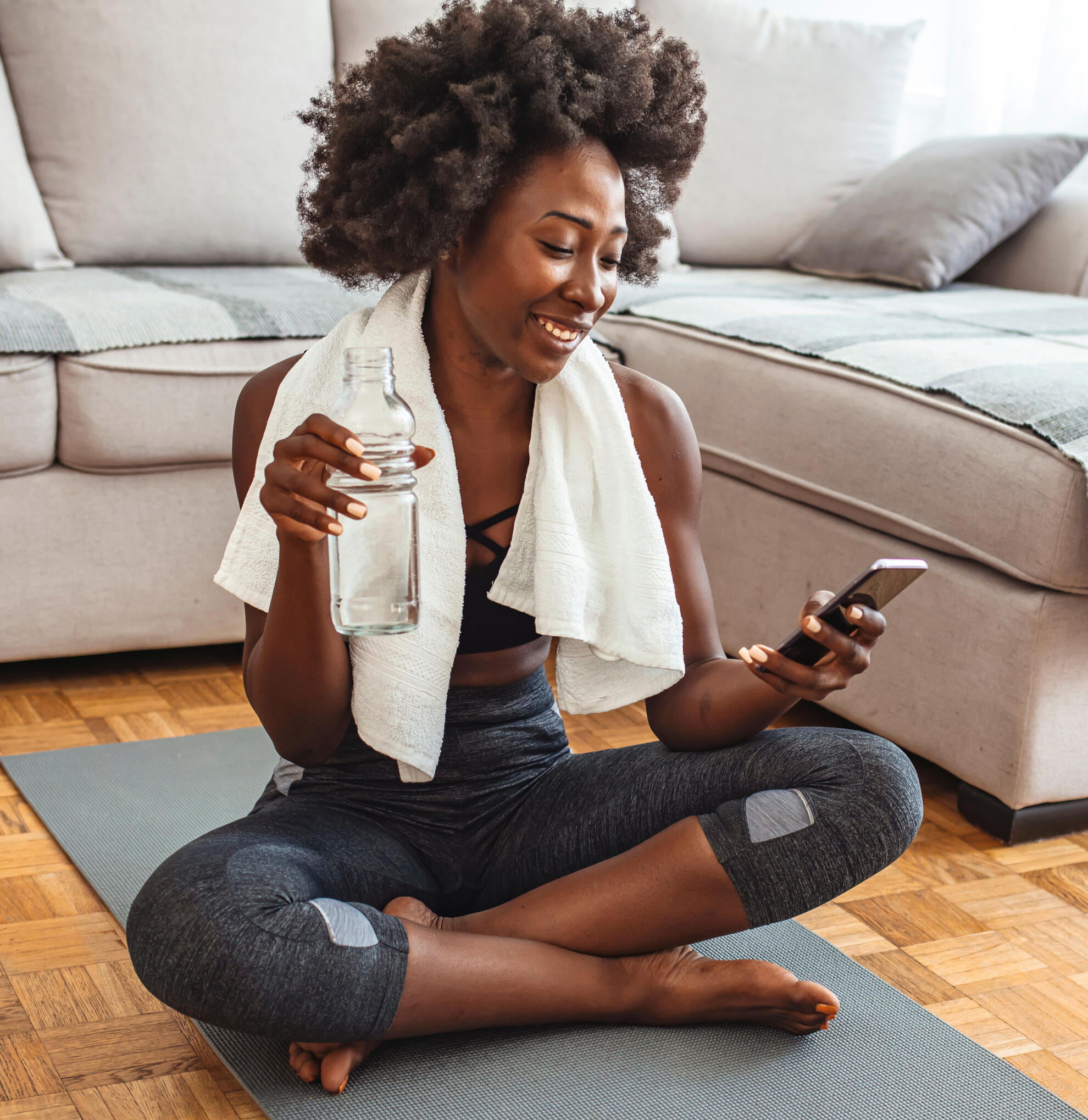Woman on a yoga mat with water bottle and phone