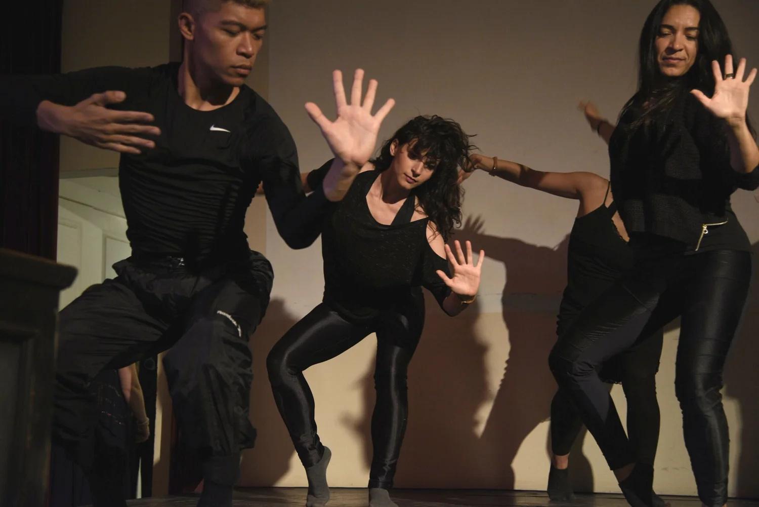 Dancers moving expressively against a warm beige wall