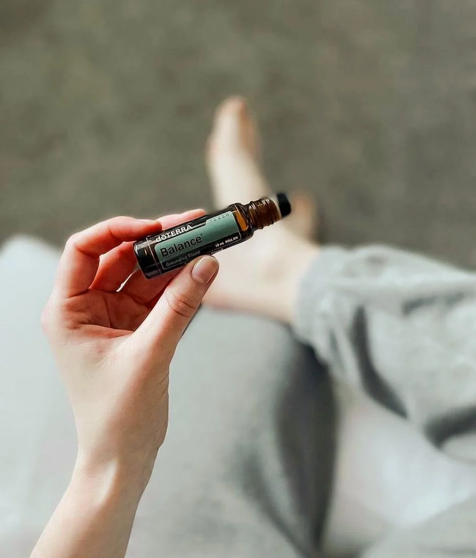 Hand holding a doTERRA Balance essential oil bottle