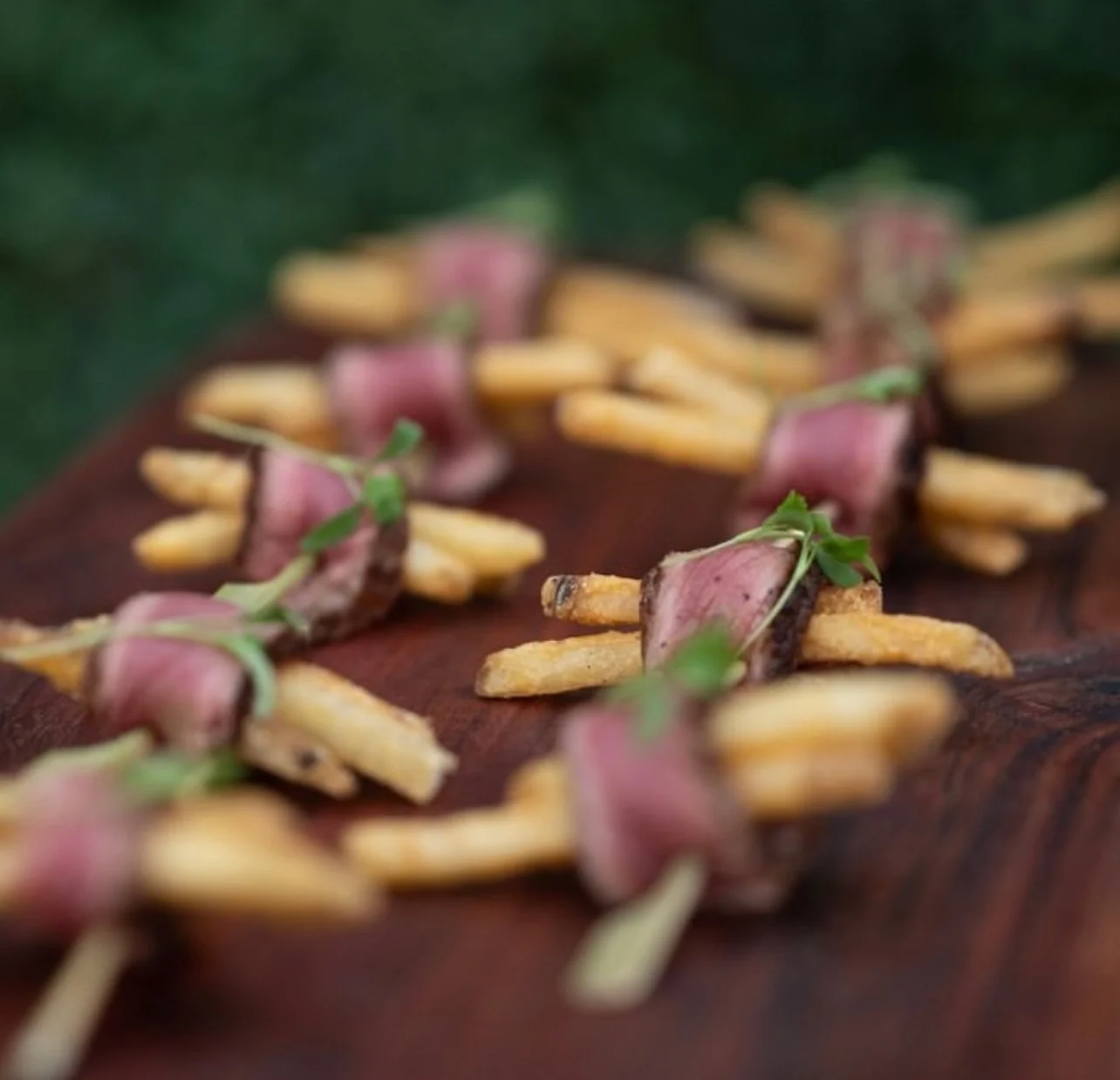 Rare sliced steak bites with fries and microgreens