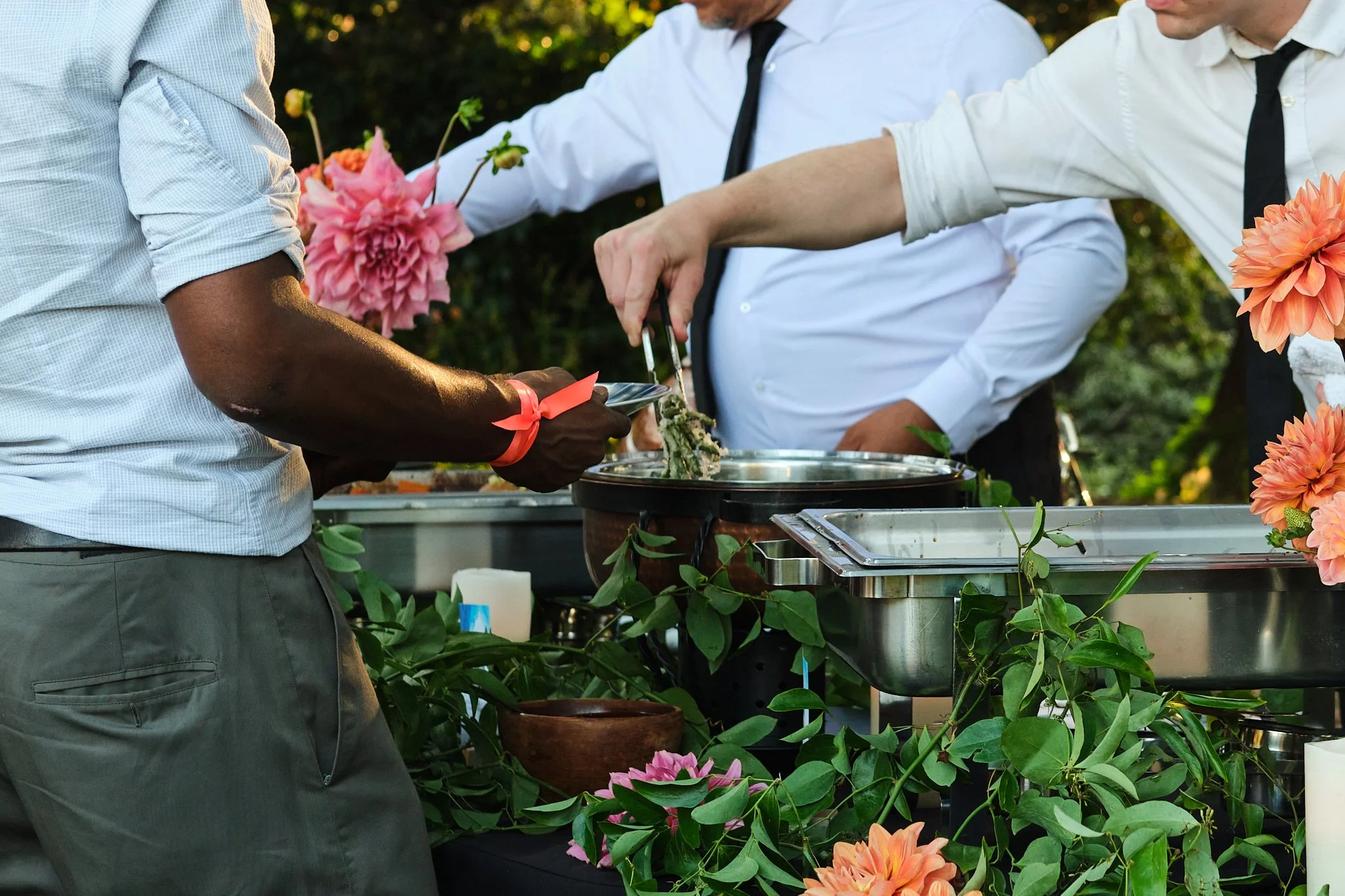 Staff serving food from chafing dishes amid dahlia decor