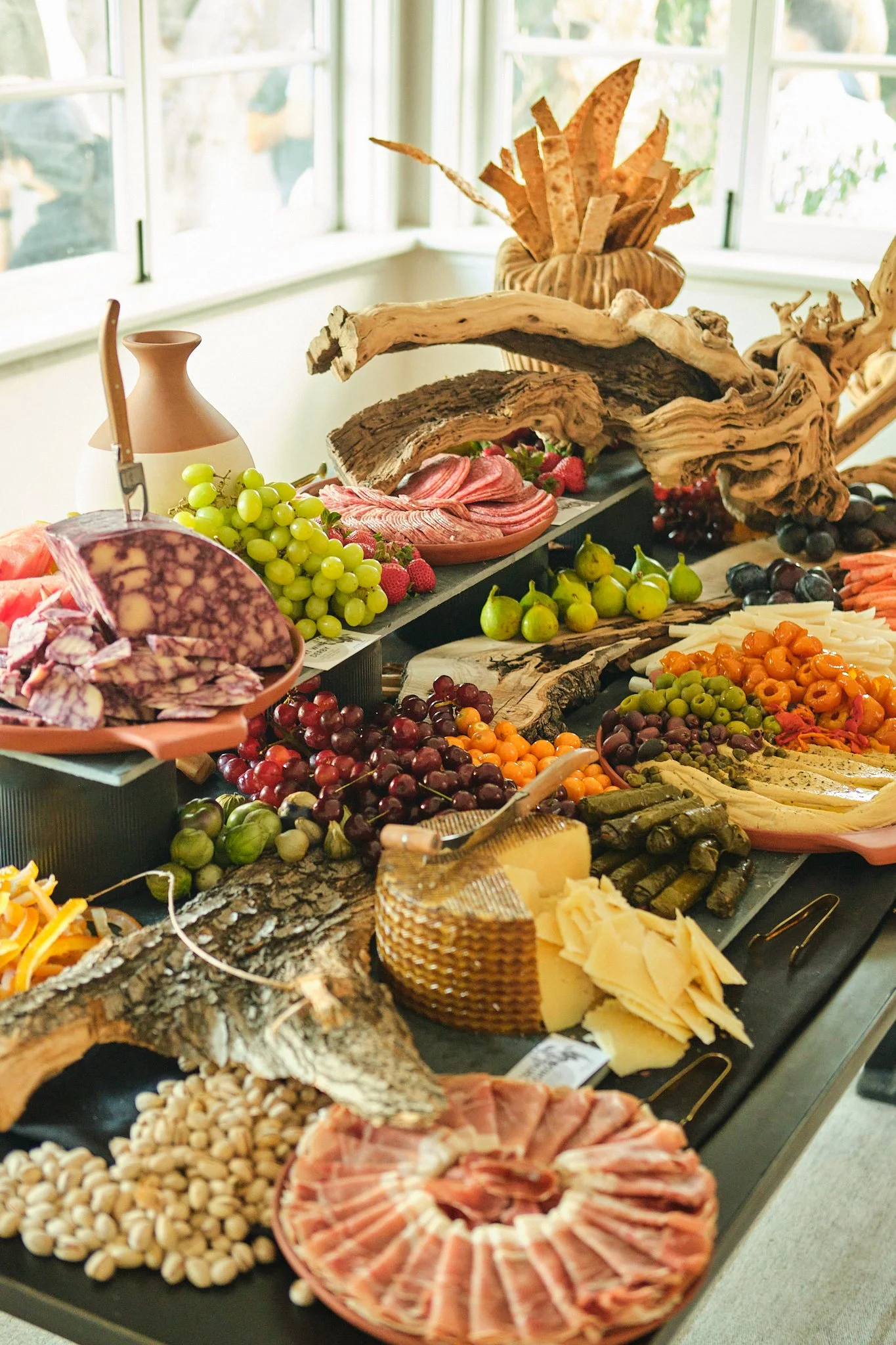 Large grazing table with charcuterie, cheeses, grapes and figs by the windows