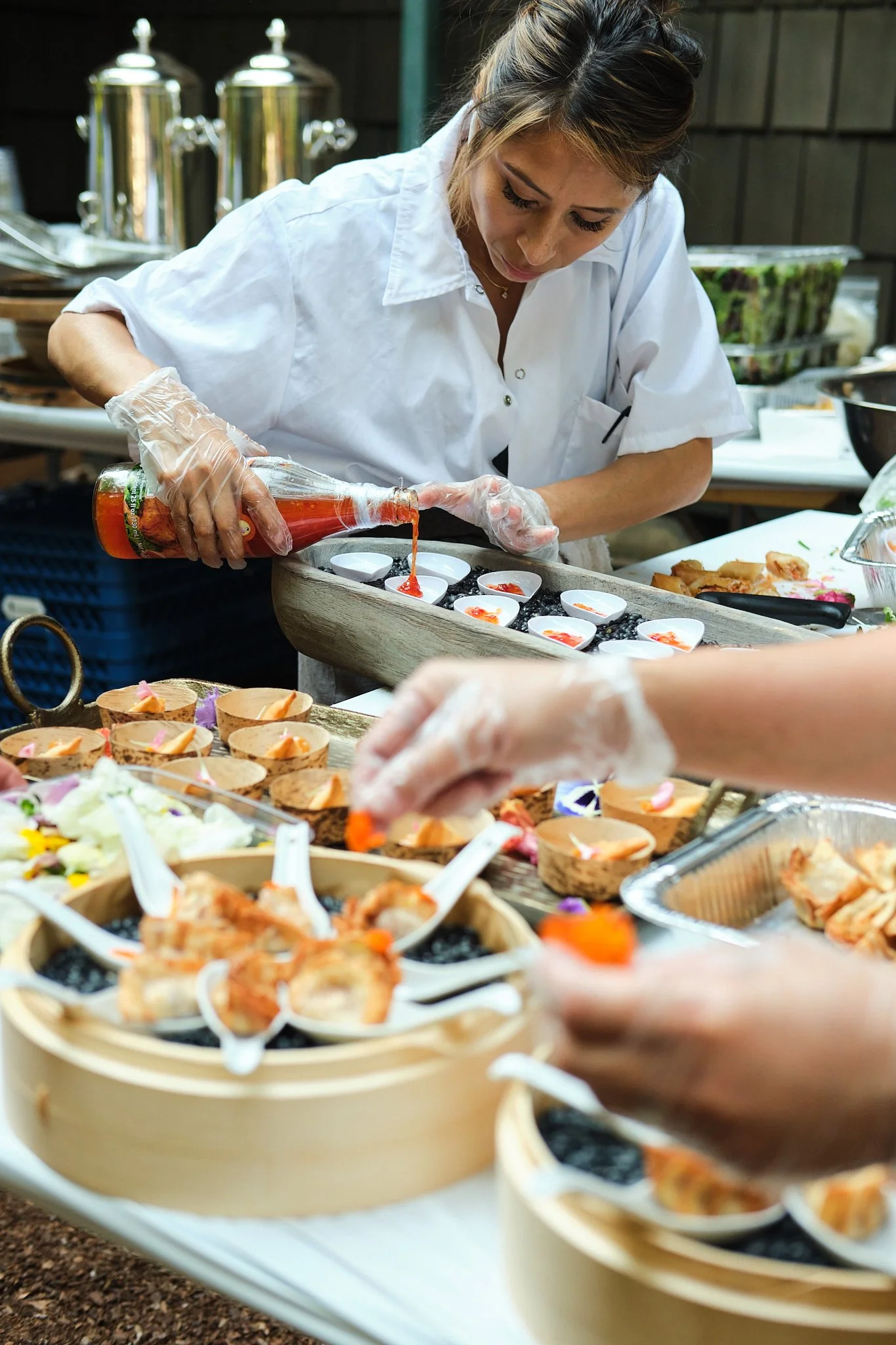 Female chef plating appetizers at an outdoor catering station