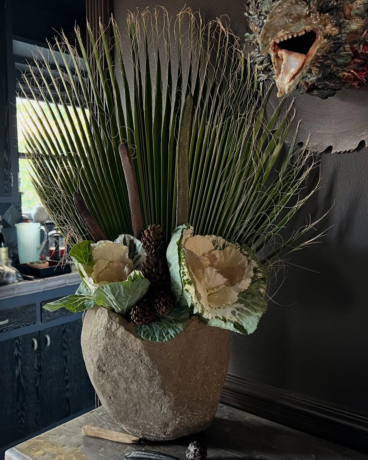 Dramatic floral arrangement with palm fronds and ornamental kale