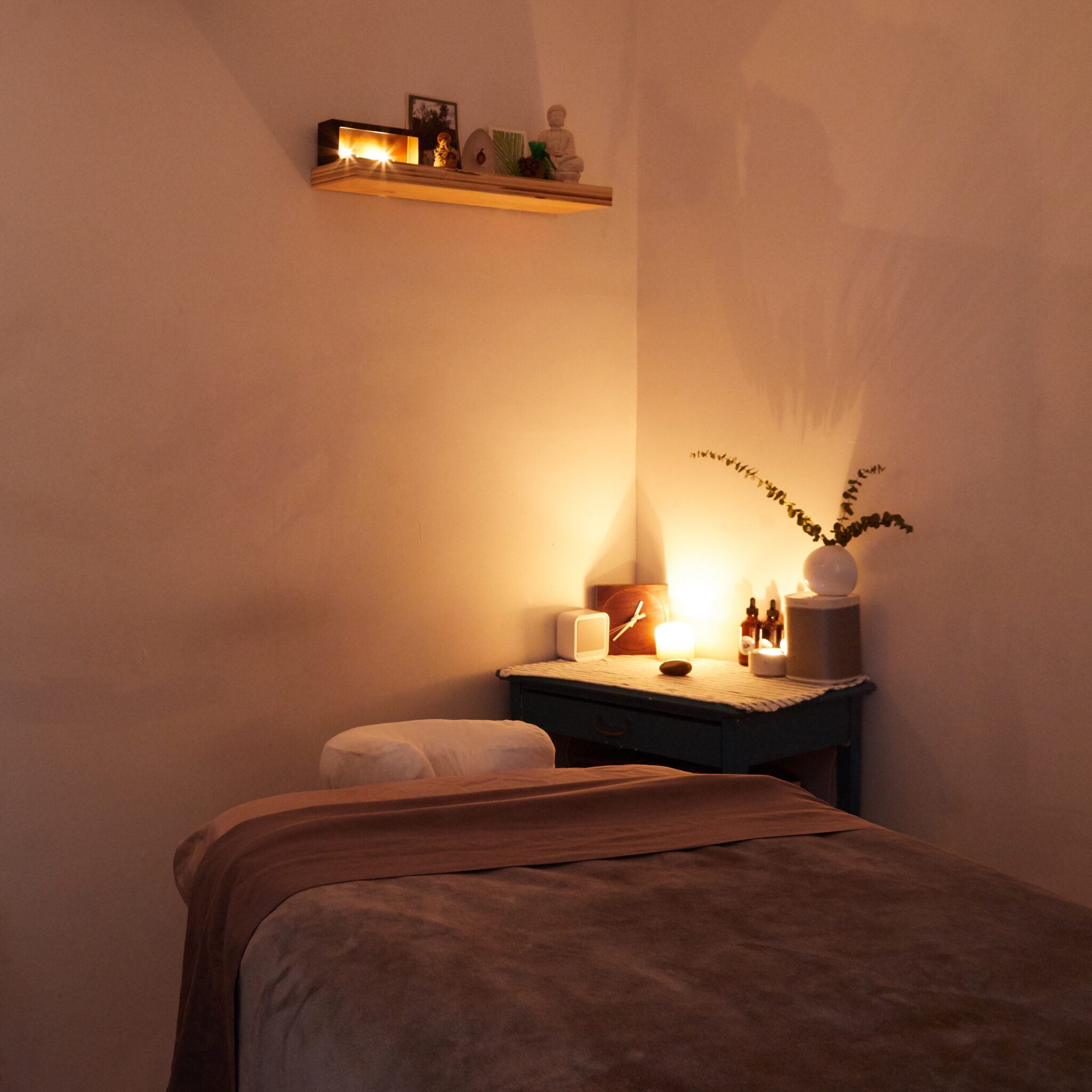 Candlelit massage treatment room with essential oils and a wooden shelf