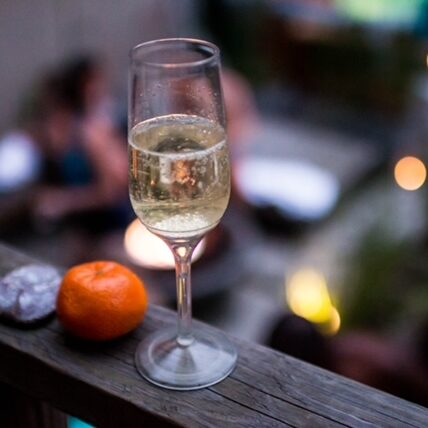 Champagne flute with a clementine on a wooden railing in the evening