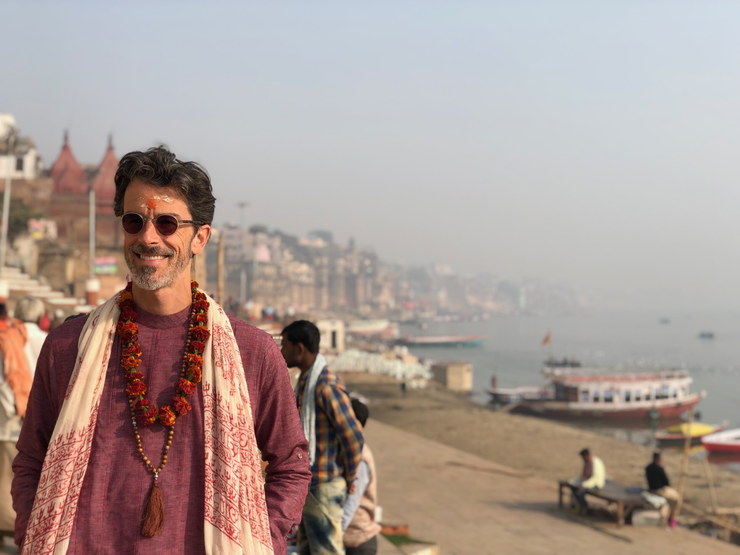 Sunrise over the river ghats of Varanasi, a lone figure wrapped in a shawl in contemplation