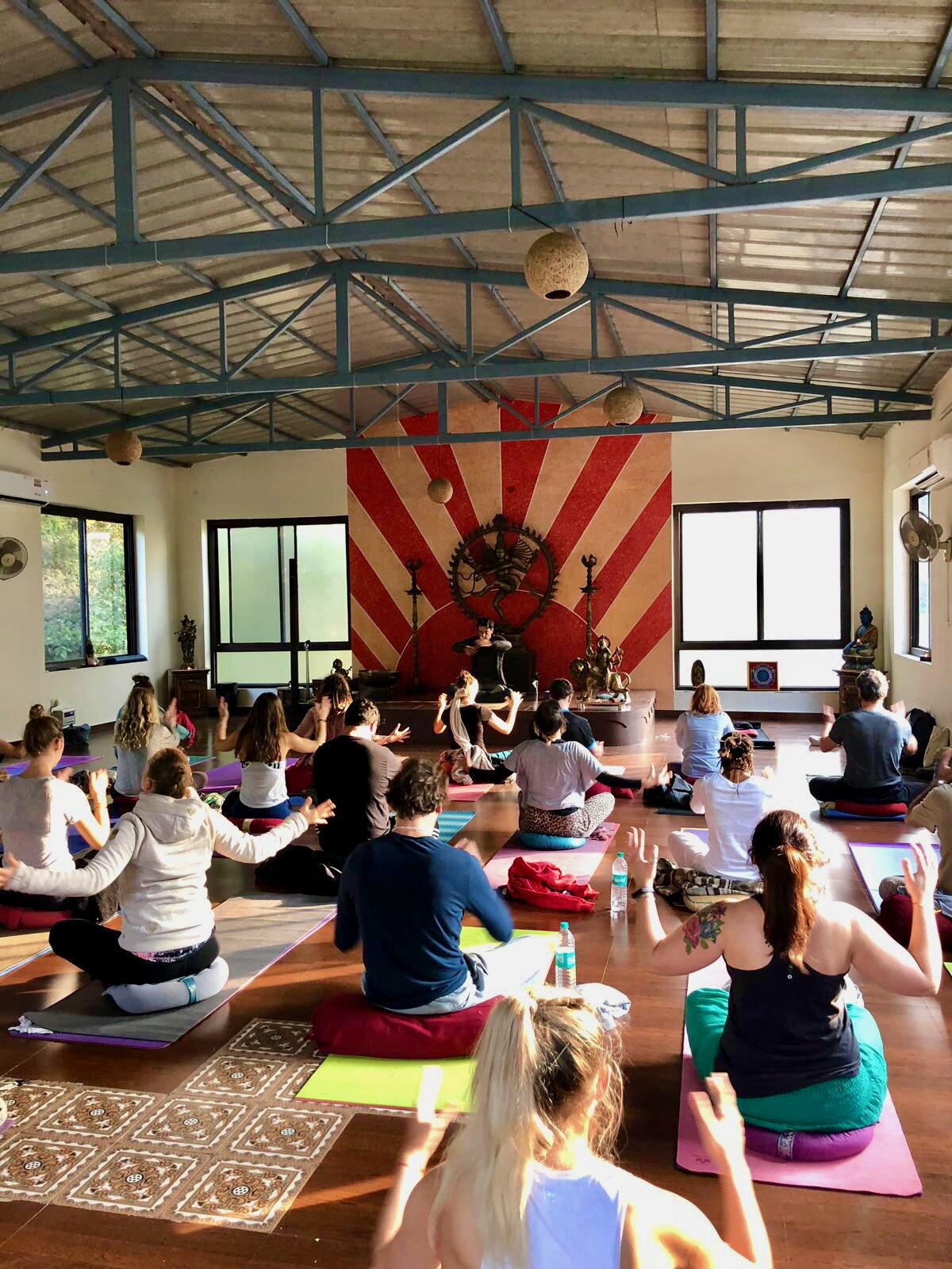 Group meditation in an Indian yoga hall with a Nataraja mural