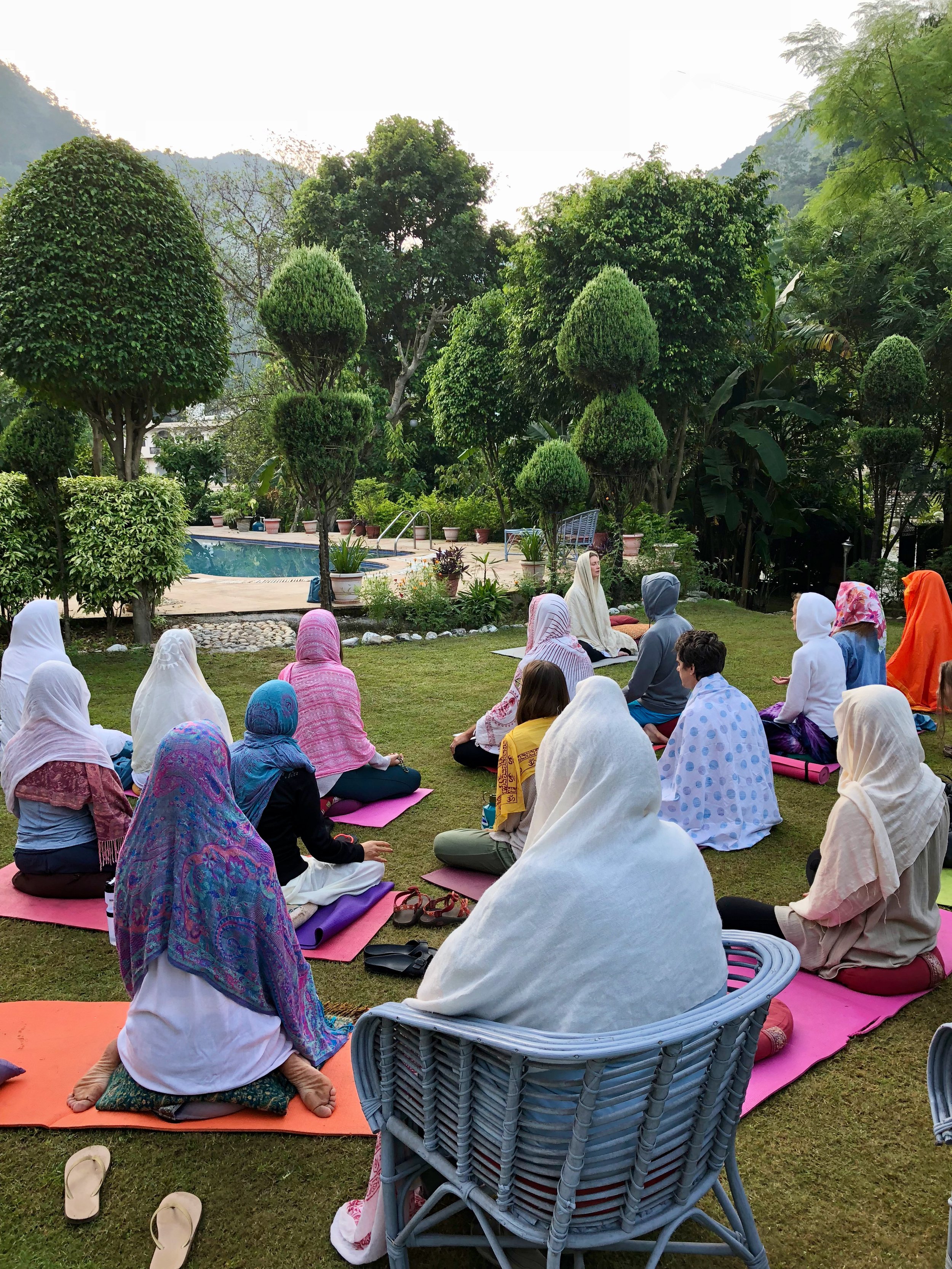 Person in orange with hands in prayer at sunrise