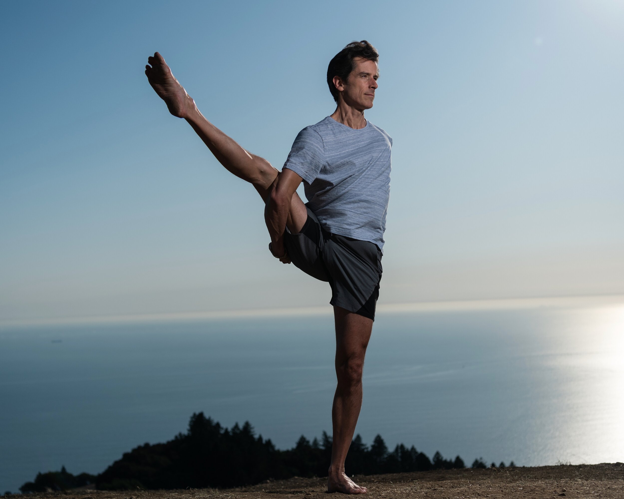 Chad in a standing yoga balance pose above the sea