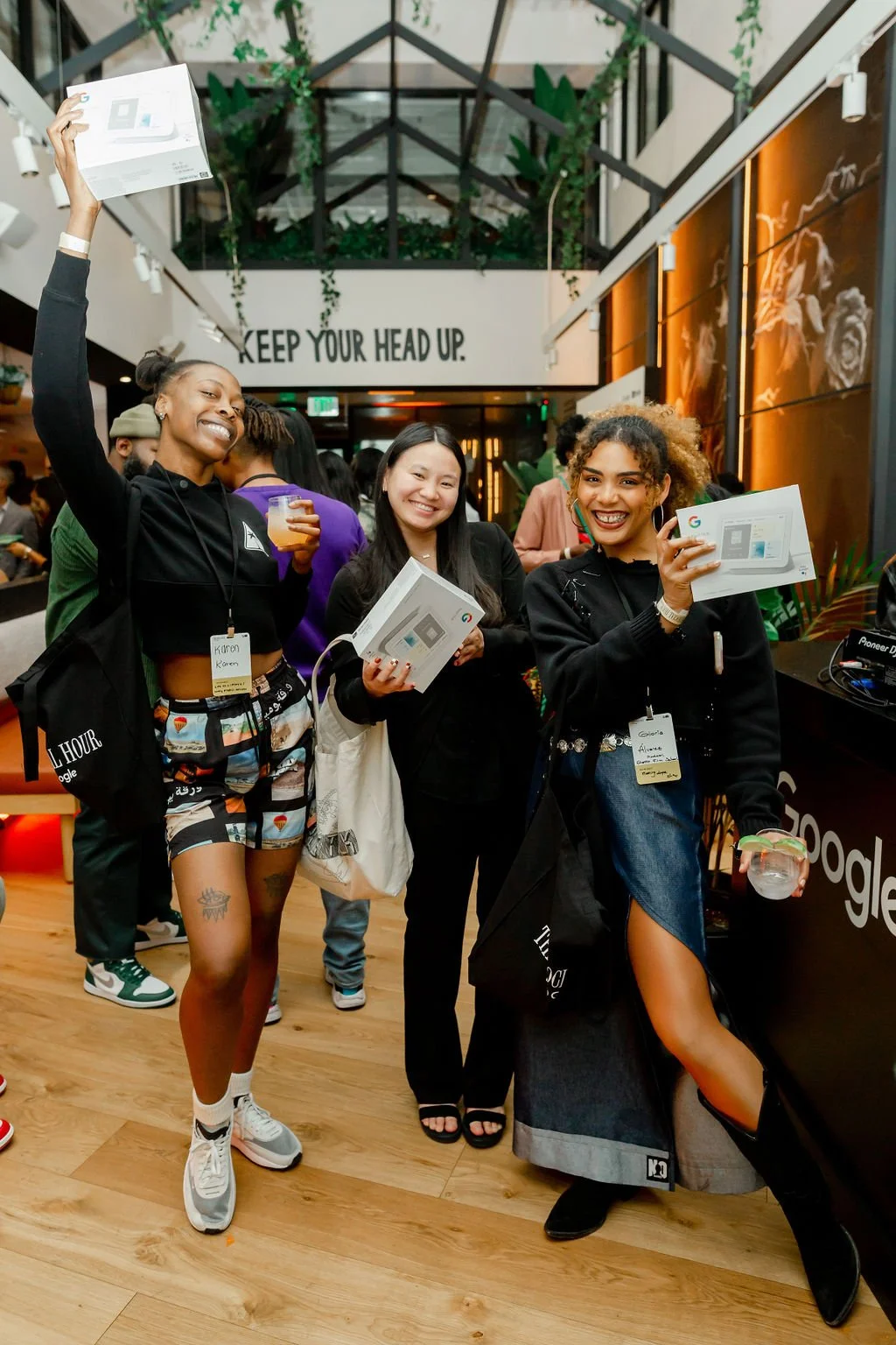 Three guests smiling and holding Google product boxes at a Social Hour event