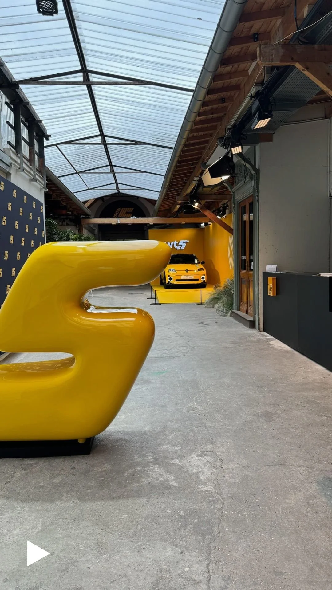 Yellow Renault 5 car on display with a glossy number five sculpture