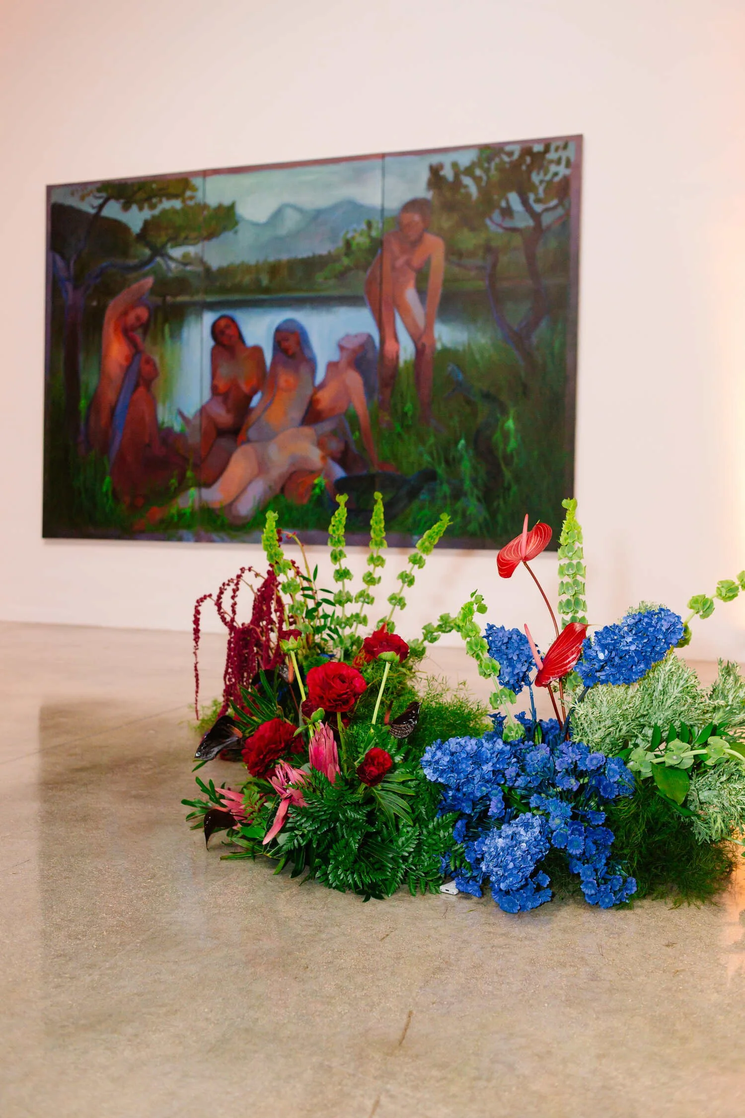 Colorful floral arrangement in front of a large figurative painting