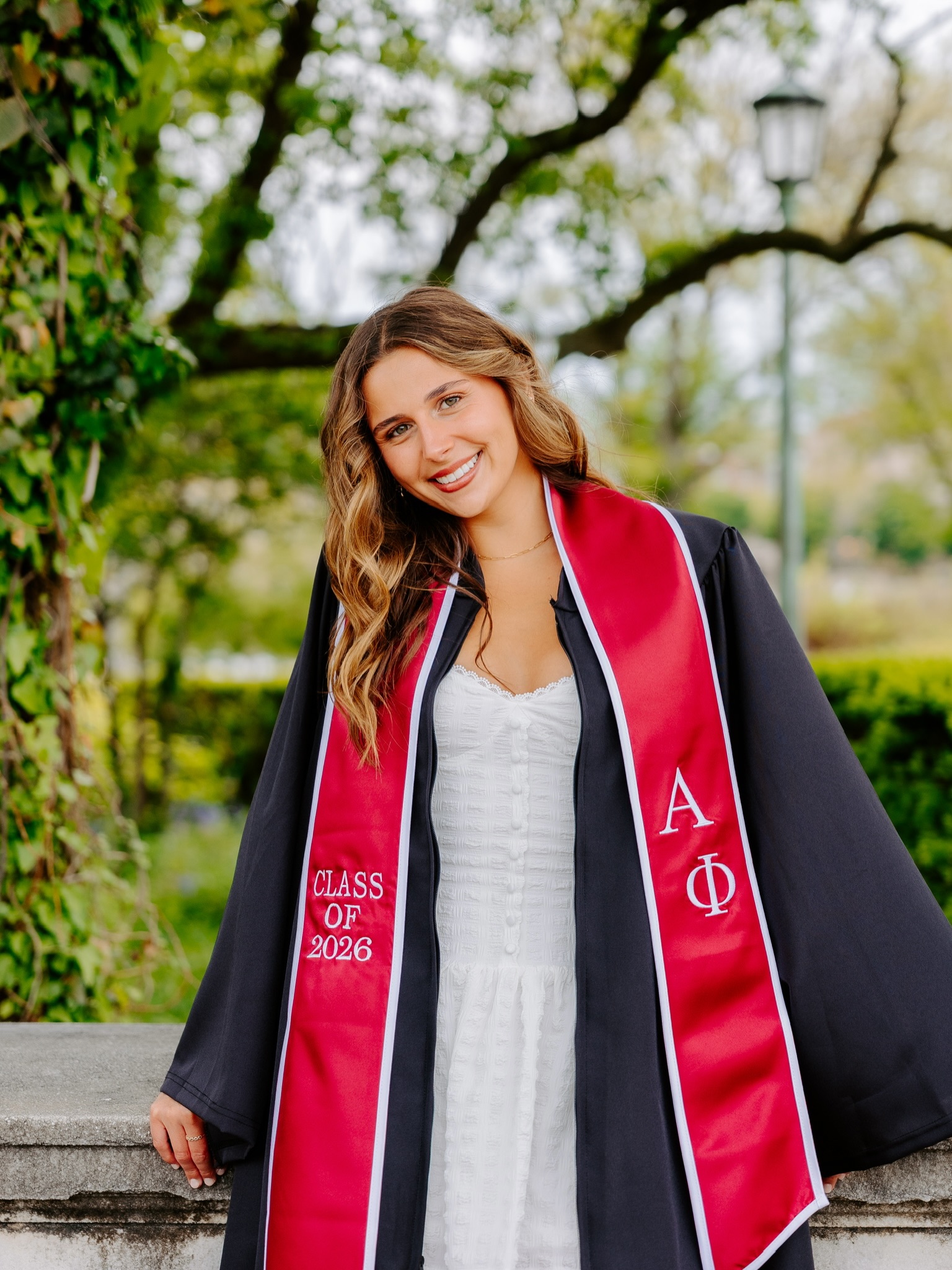 Young woman in graduation gown and Alpha Phi sash smiling