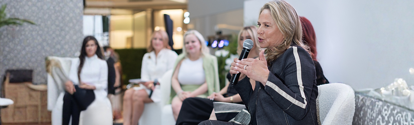 Michelle Valenzuela Wolf speaking into a microphone at a women's event panel