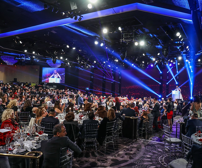 Corporate gala ballroom with blue stage lighting and packed round tables