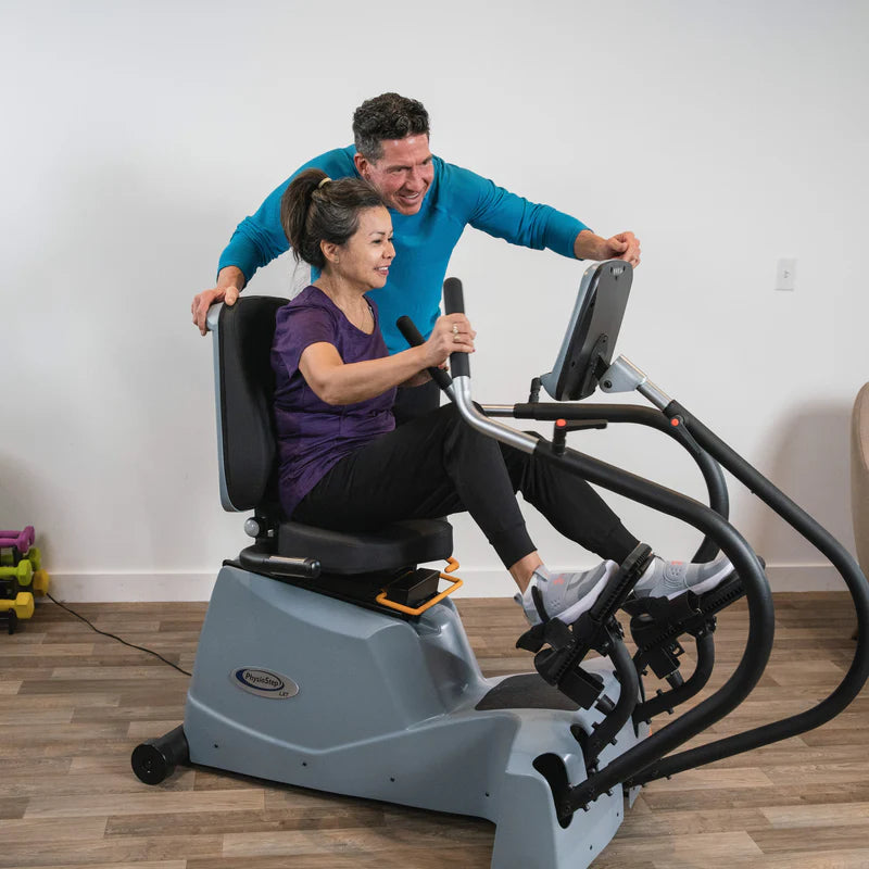 HCI PhysioStep LXT Recumbent Stepper with trainer assisting