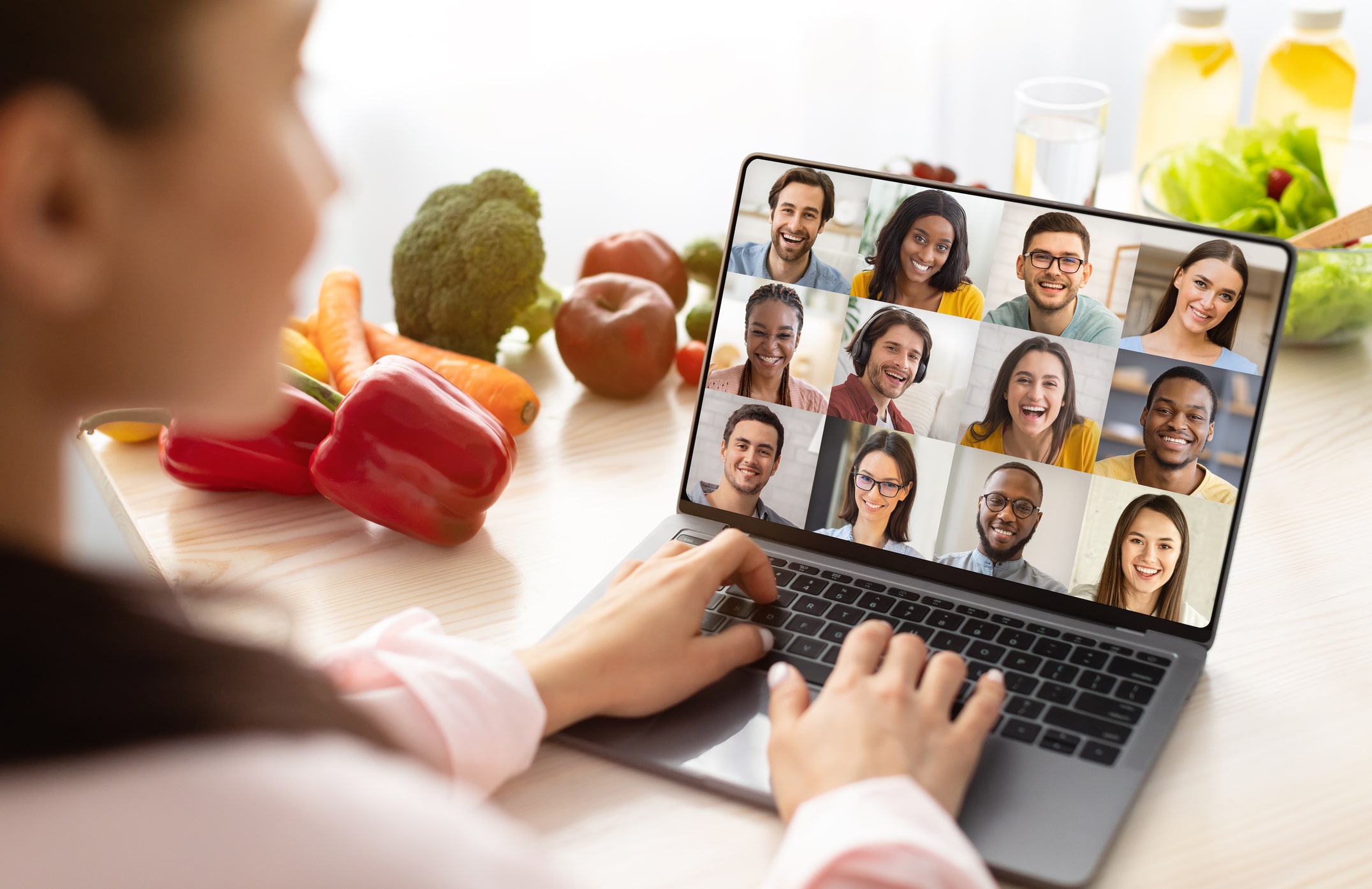 Woman on a laptop group video call with fresh vegetables nearby