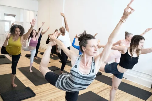 ISHTA students in a standing balance pose in the bright NYC studio