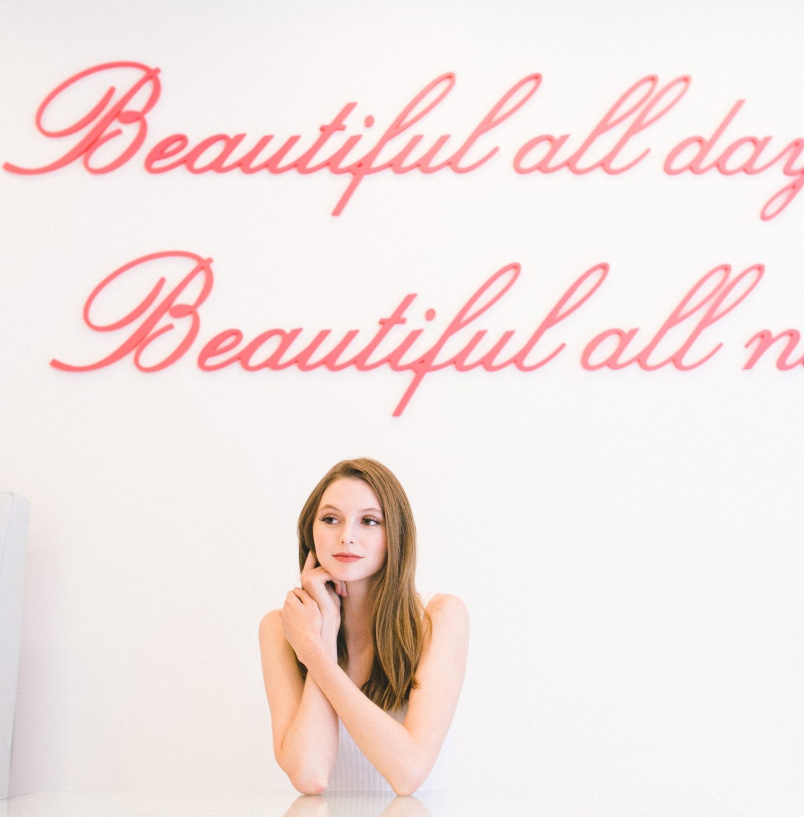 Woman seated by the JJ Eyelashes neon wall sign