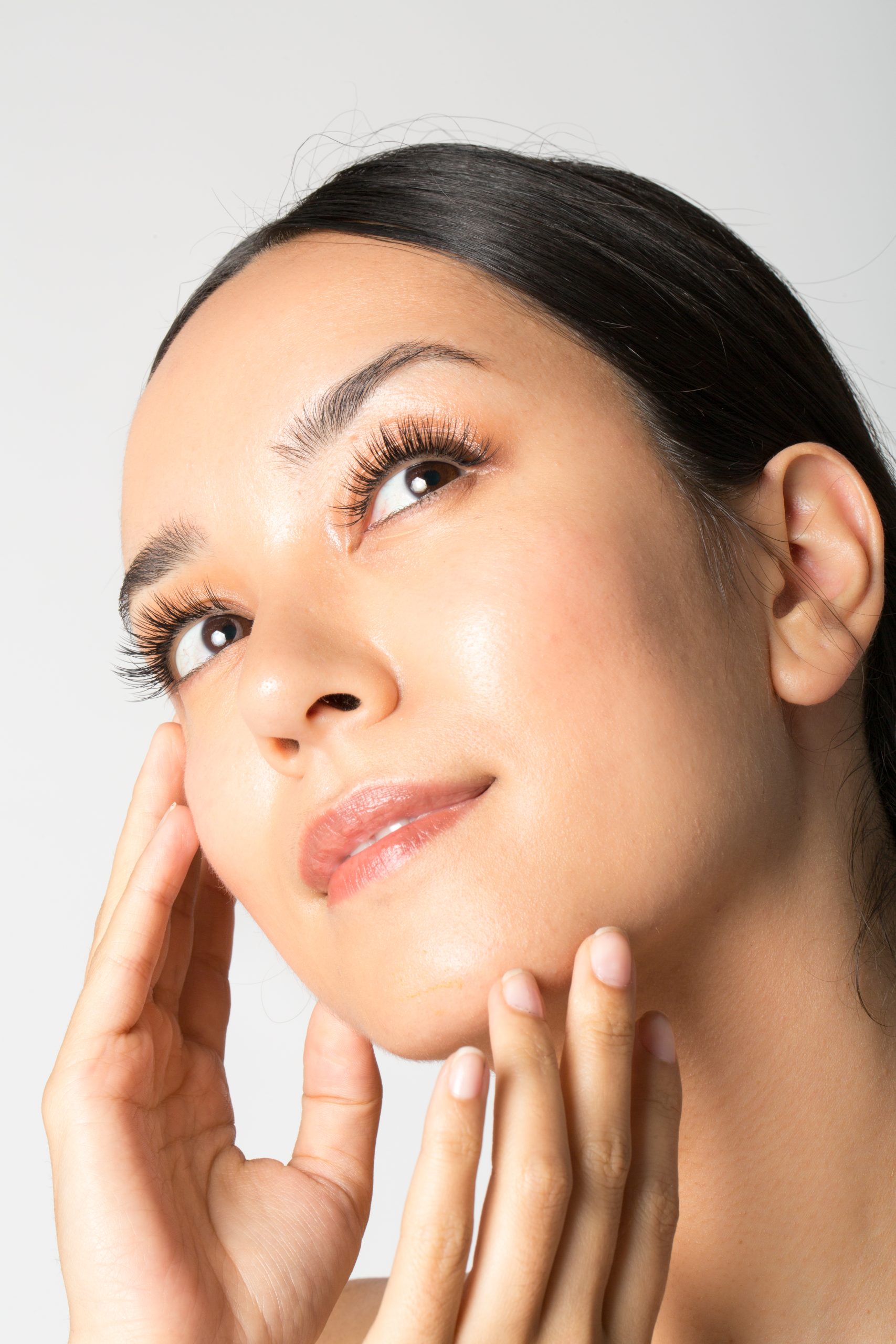 Woman framing her face with her hands, showing natural lash extensions