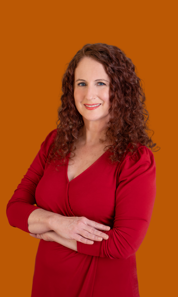 Erica Mesirov, wellness consultant, smiling with arms crossed in a red dress