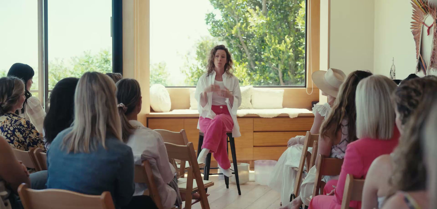 Kelsey in a white blazer speaking to a seated group