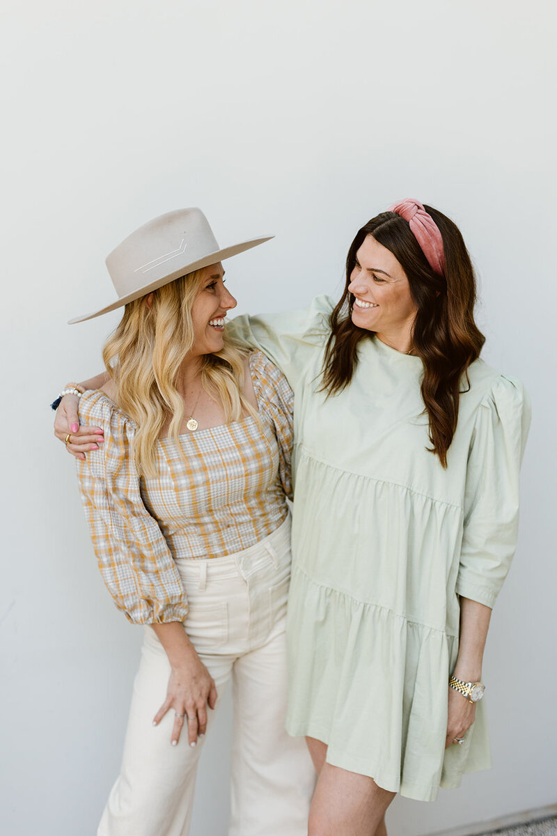 Sarah and Kiersten of LB Events laughing together against a white wall