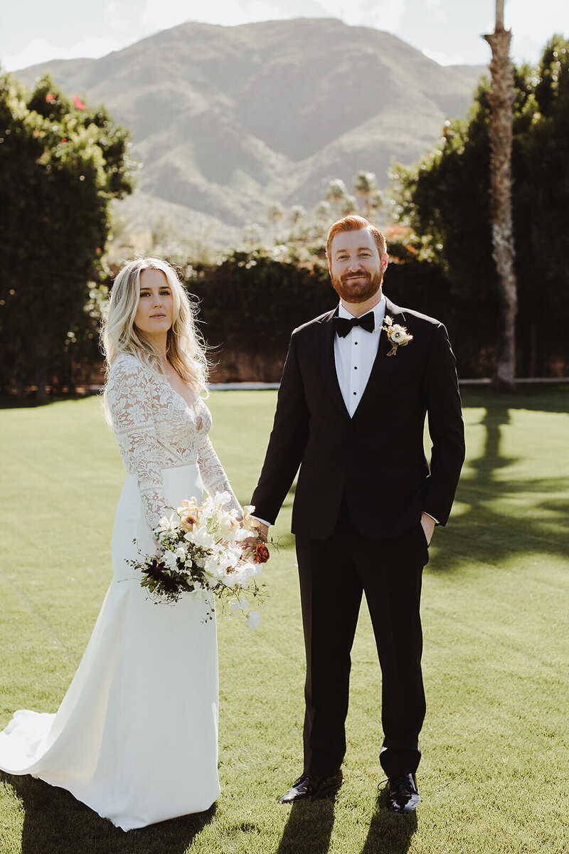 Couple on a lawn with a mountain backdrop; bride in a long-sleeve lace gown — Margaret and Steve