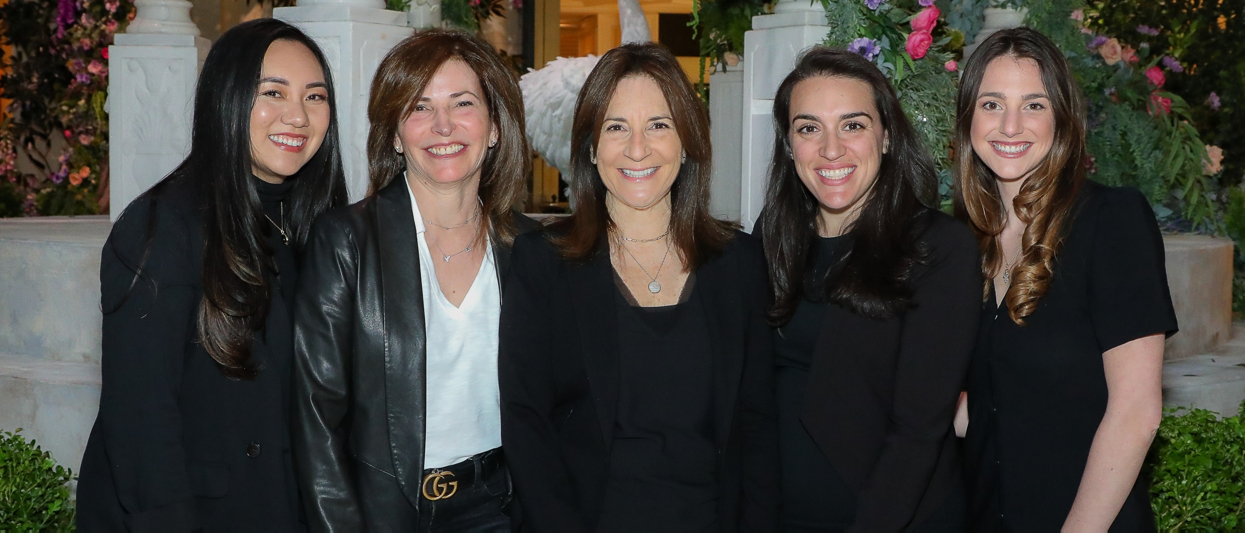 The MCPI team — five women at an event with a floral backdrop
