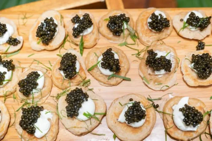 Caviar blinis arranged on a wooden board — luxury catering detail