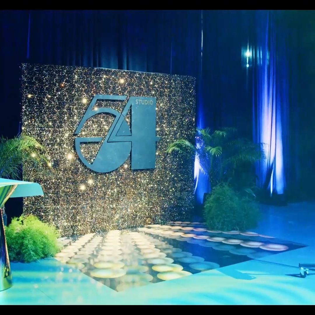 Studio 54-themed event décor with glittery sequin backdrop and blue theatrical lighting