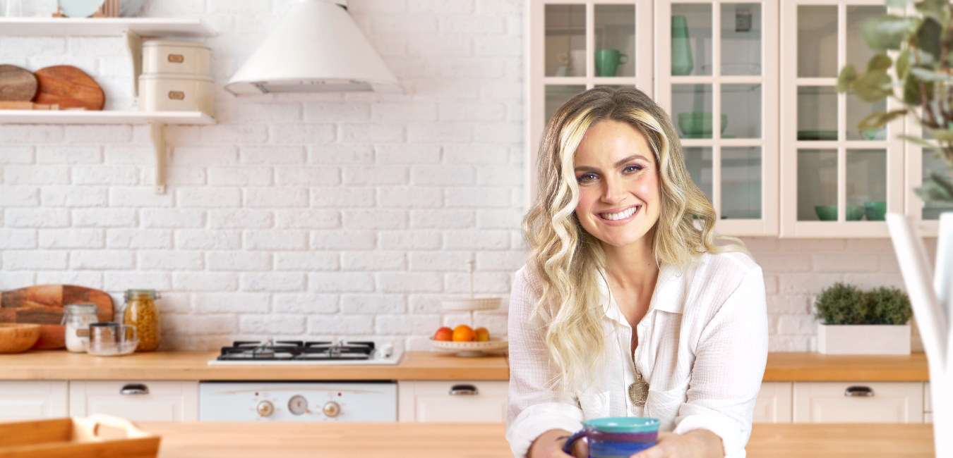 Alex, integrative dietitian, smiling and holding a mug in a bright white kitchen