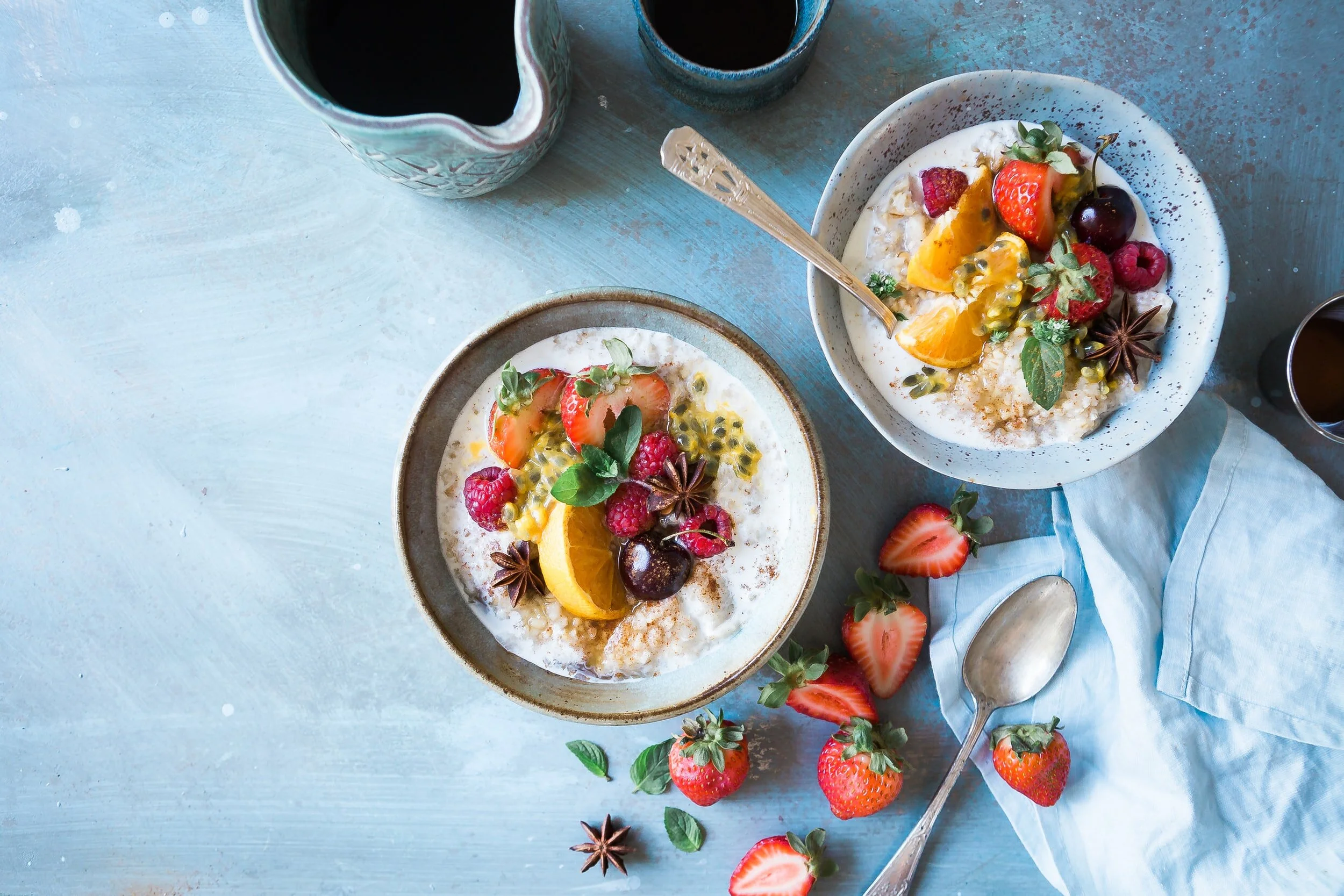 Two bowls of oatmeal topped with fresh fruit and berries