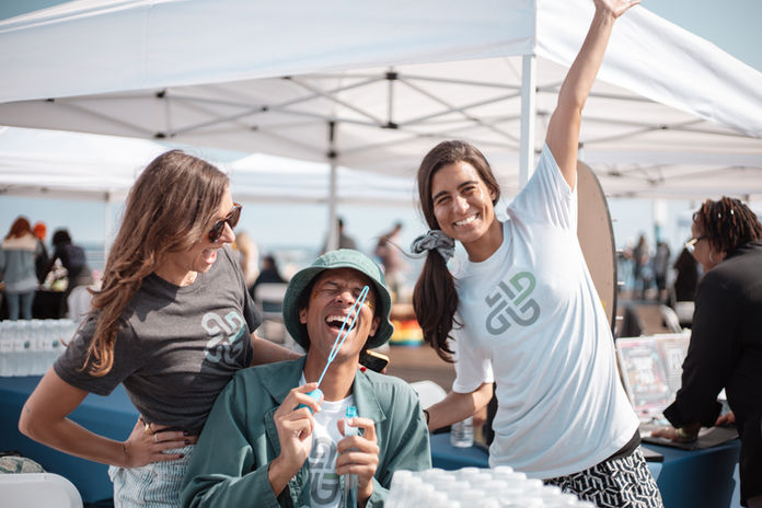 Three people laughing and celebrating at an oceanside event booth