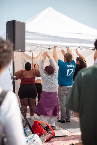Group of people with arms raised in a wellness activity under a white tent