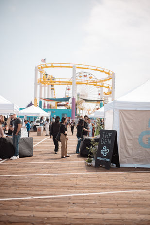 The Den Meditation sign with the Santa Monica Pier roller coaster in the background