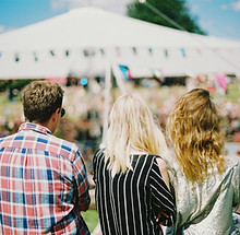 Audience watching an outdoor event with a white tent stage