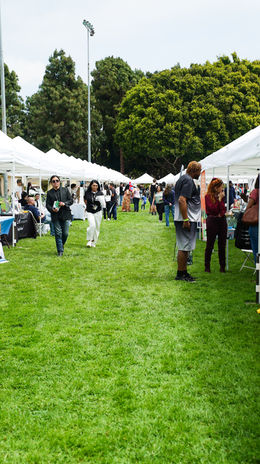 Aisle between white vendor tents at an outdoor community event